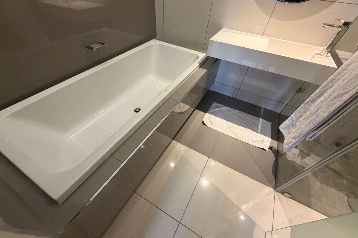 Modern bathroom featuring a sleek built-in bathtub, wall-mounted basin with chrome fixtures, and contemporary large-format wall and floor tiling.