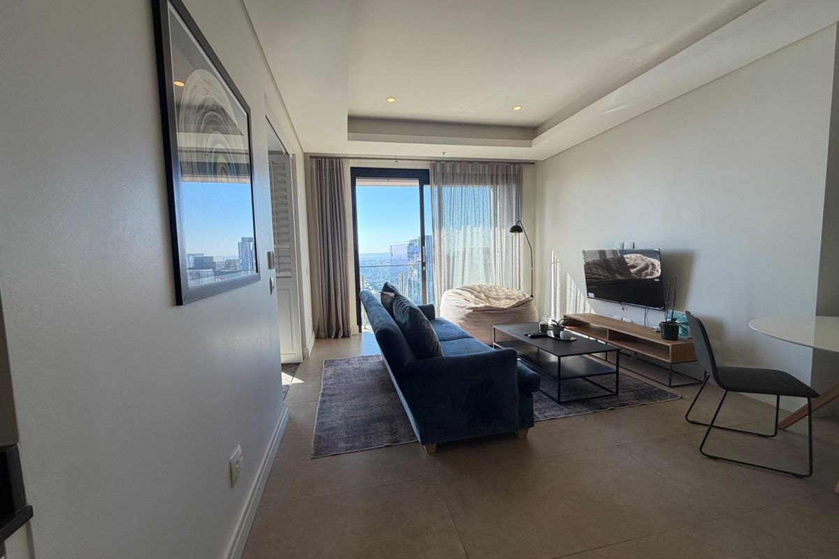 Modern living room featuring tiled flooring, recessed ceiling lighting, and large sliding glass doors leading to a balcony with city views.