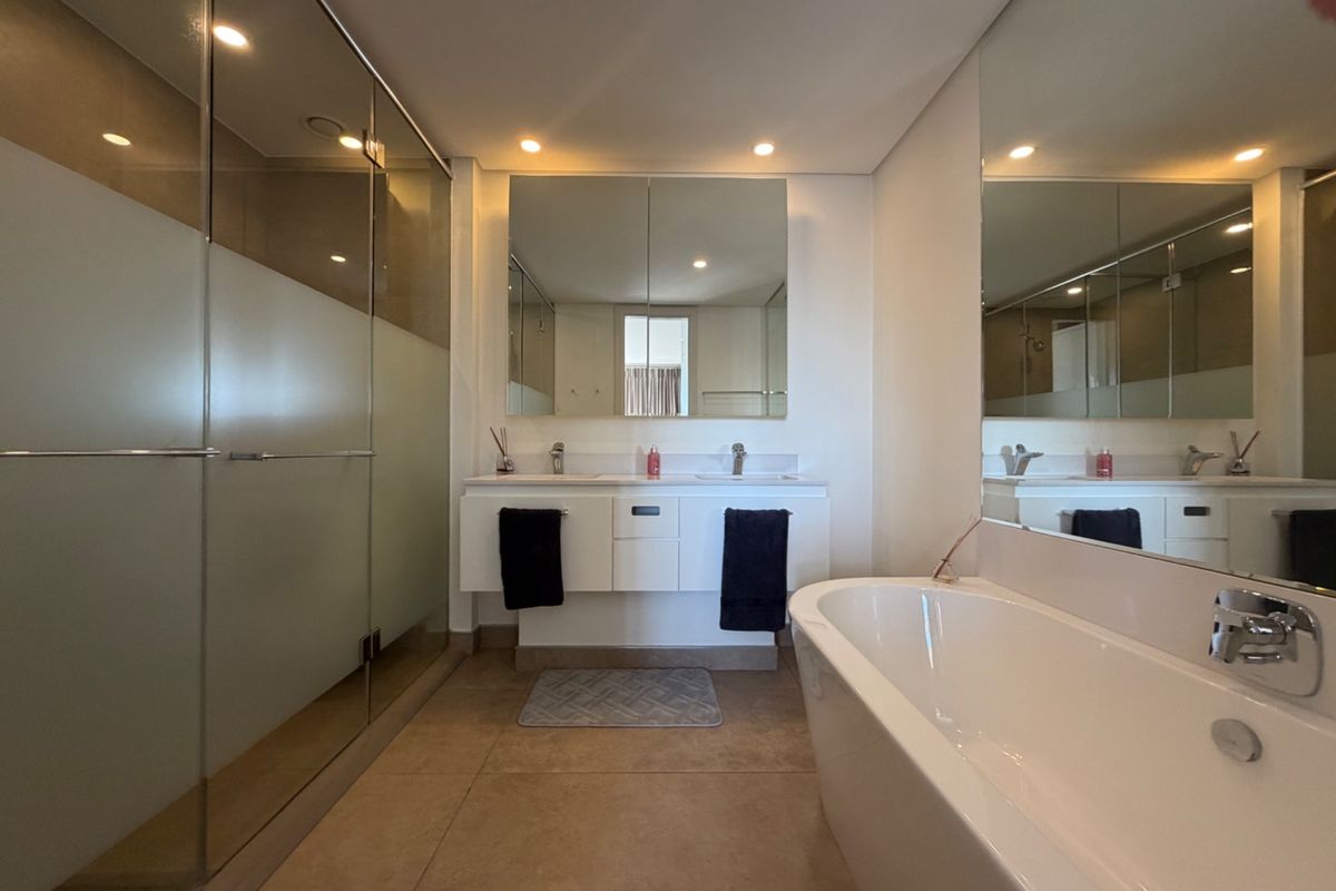Modern bathroom featuring a double vanity, a sleek freestanding bathtub, and a spacious glass-enclosed shower with contemporary finishes and recessed lighting.