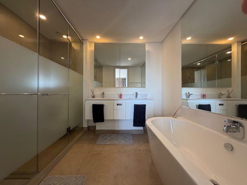 Modern bathroom featuring a double vanity, a sleek freestanding bathtub, and a spacious glass-enclosed shower with contemporary finishes and recessed lighting.