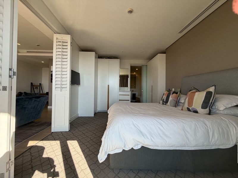 Spacious bedroom featuring built-in cupboards, carpeted flooring, recessed lighting, and direct access to an en-suite bathroom.