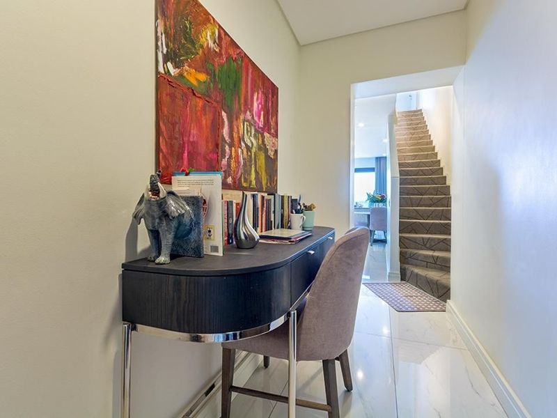 A bright hallway featuring polished marble-look floor tiles and a staircase leading to the upper level.