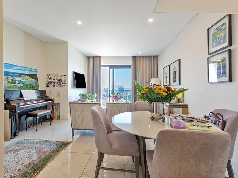 Bright open-plan living and dining area featuring polished marble-look floor tiles, recessed lighting, and direct access to a balcony with city views.
