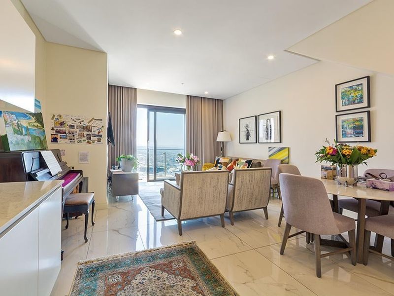 Spacious open-plan living and dining area featuring polished marble-look floor tiles, recessed lighting, and seamless access to a balcony with expansive views.