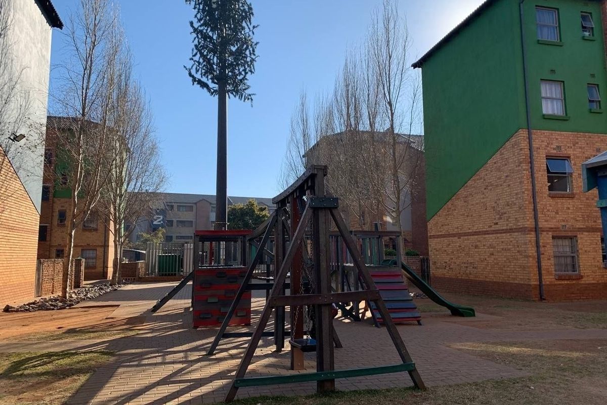 Communal outdoor courtyard area featuring a paved surface and playground equipment situated between apartment building blocks.