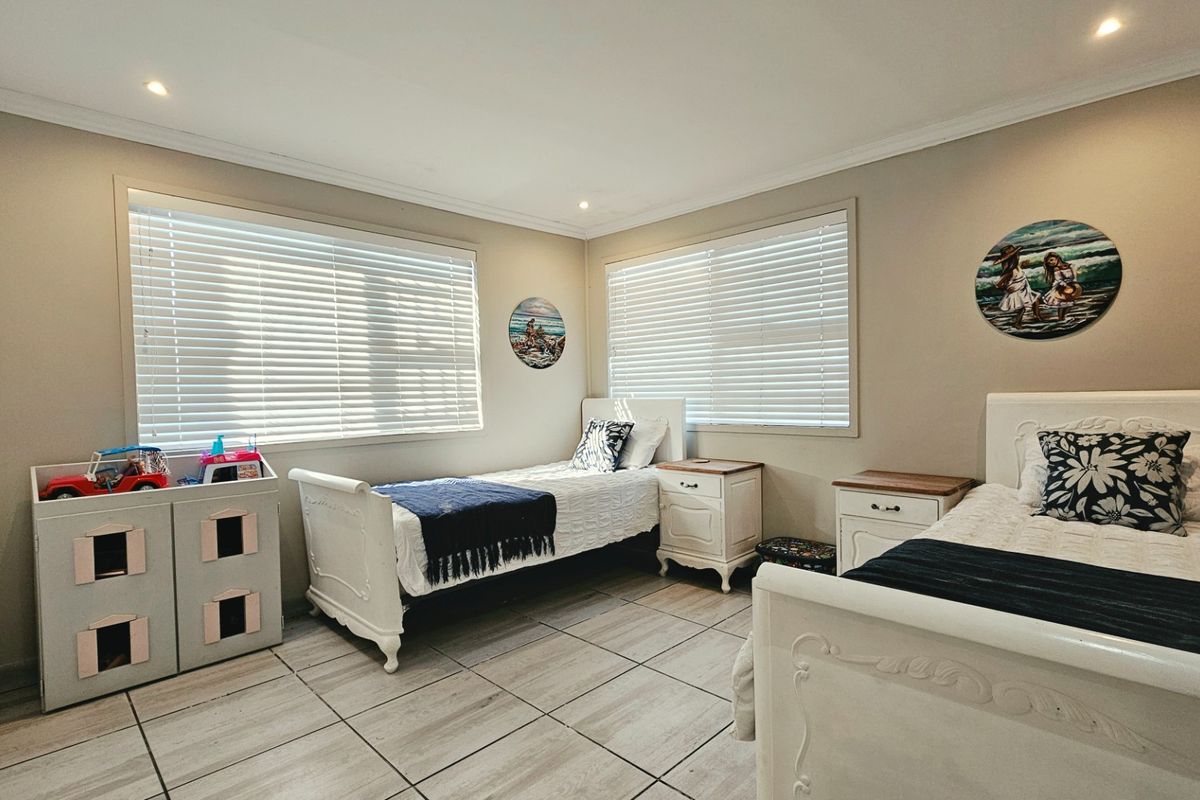 A well-maintained bedroom featuring tiled flooring, recessed downlighting, and venetian blinds, offering a clean and functional living space.