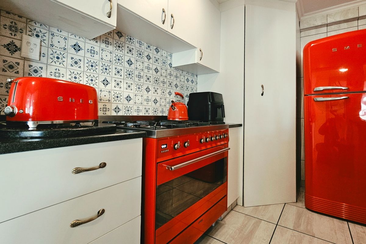 A compact kitchen featuring white cabinetry, a patterned tile backsplash, stone countertops, and a gas stove with an integrated oven.