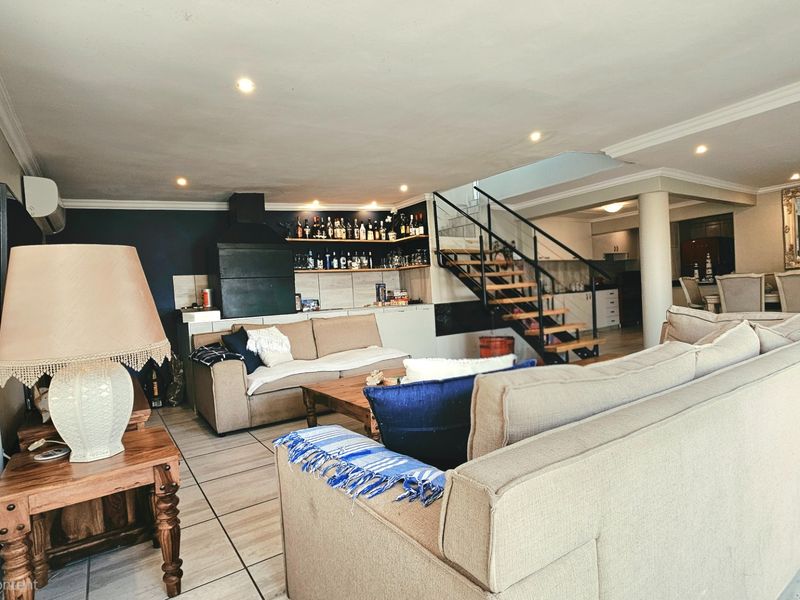 Spacious open-plan living area featuring a built-in fireplace, modern staircase, and tiled flooring, creating a functional and connected layout for the home.