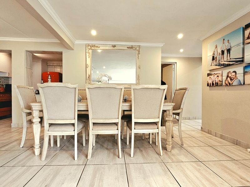 An open-plan dining area featuring tiled flooring and recessed lighting, seamlessly connected to a functional kitchen space with built-in cabinetry and appliances.