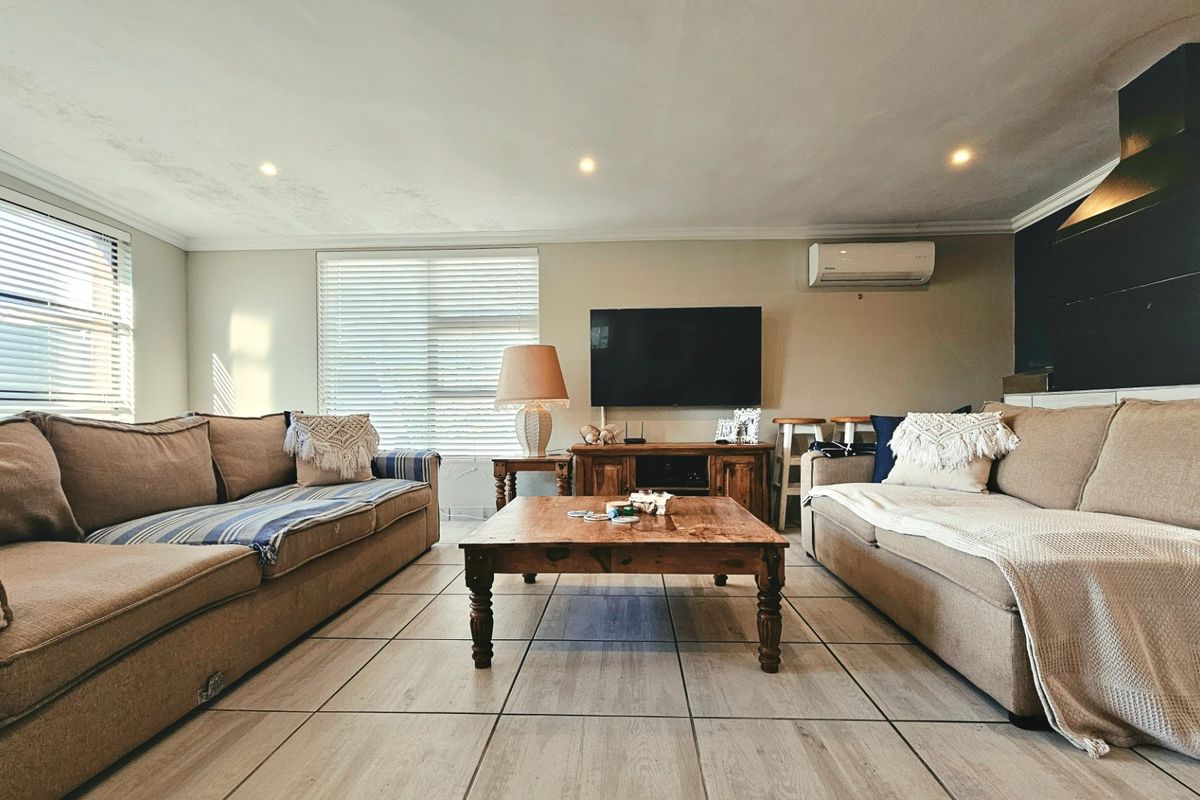 A comfortable living room featuring tiled flooring, recessed downlighting, a split-system air conditioner, and a fireplace chimney breast.