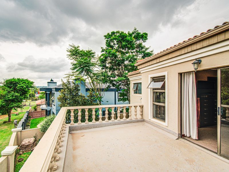 An elevated balcony featuring a classic balustrade, sliding door access to the interior, and views over the surrounding residential estate.