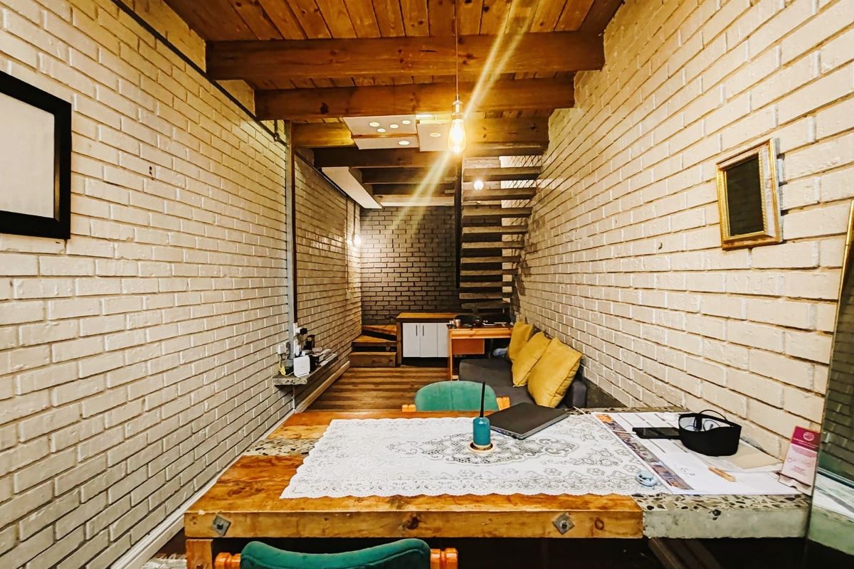 An open-plan commercial space featuring exposed brick walls, timber ceiling beams, and a wooden staircase, offering a rustic and industrial aesthetic.