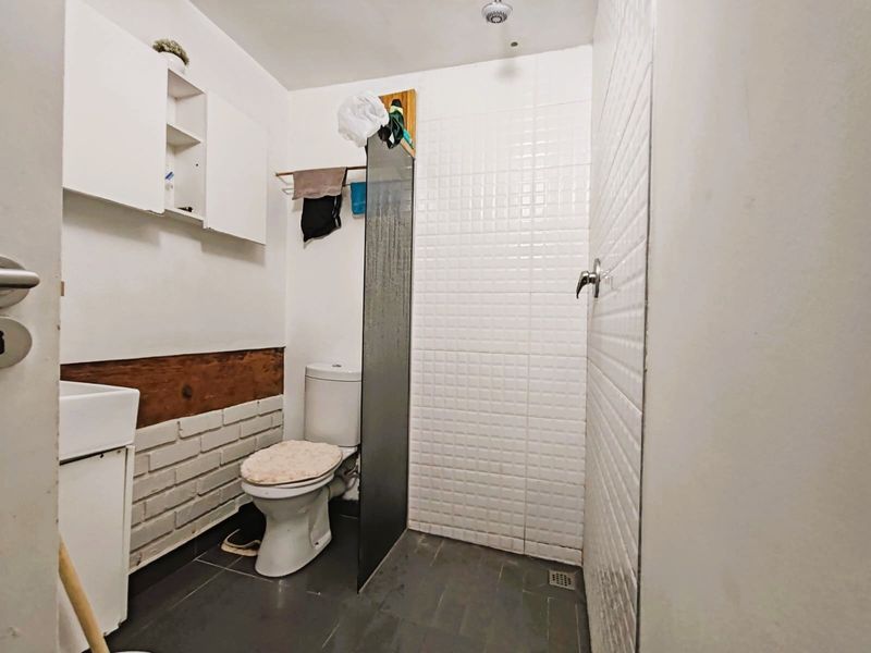 A compact bathroom featuring a walk-in shower with a glass screen, tiled walls, and a wall-mounted vanity unit.