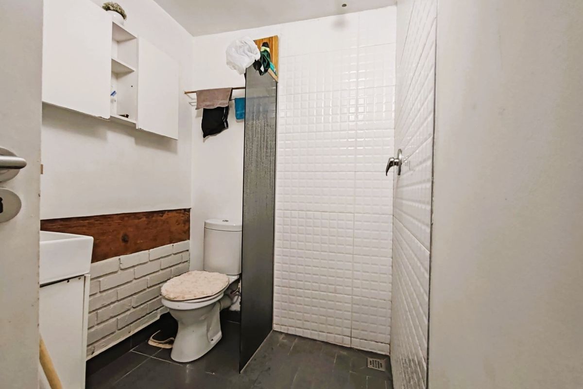 A compact bathroom featuring a walk-in shower with a glass screen, tiled walls, and a wall-mounted vanity unit.
