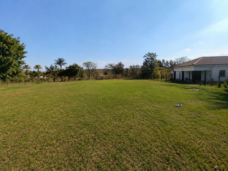 A spacious, well-maintained lawn area surrounding the property, featuring perimeter fencing and clear views of the surrounding landscape.