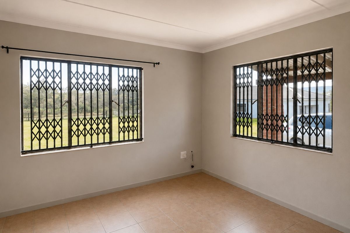 A bright, empty bedroom featuring neutral walls, tiled flooring, and security gates on the windows, providing a clean and secure blank canvas.