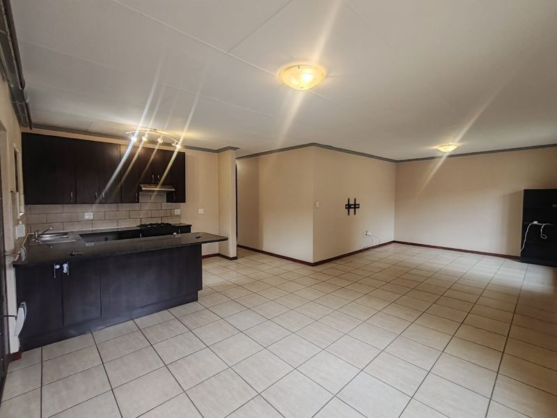 Spacious open-plan living area featuring a modern kitchen with dark cabinetry, granite countertops, and tiled flooring throughout.
