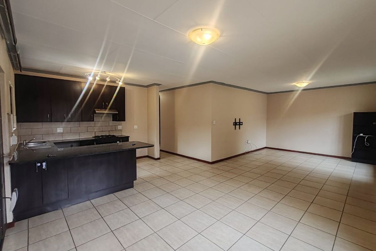 Spacious open-plan living area featuring a modern kitchen with dark cabinetry, granite countertops, and tiled flooring throughout.