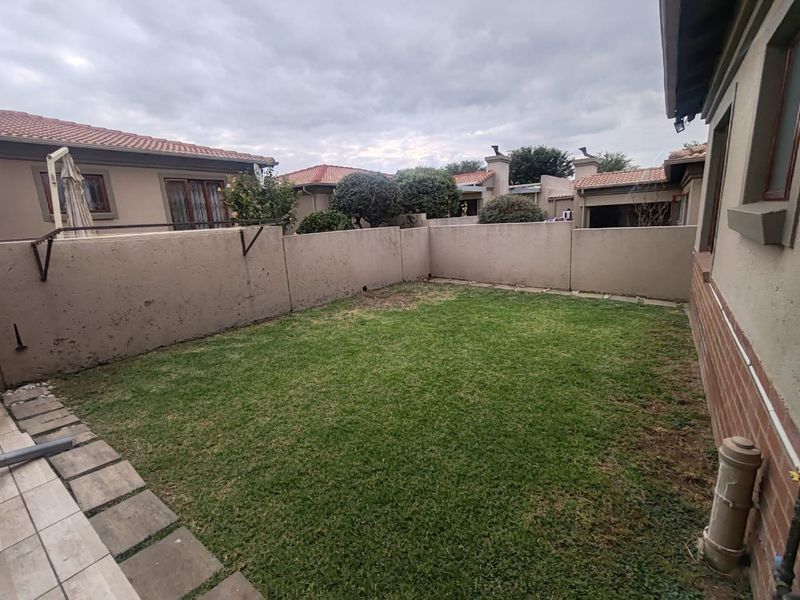 A private rear garden area featuring a lawn, paved walkway, and perimeter boundary walls.
