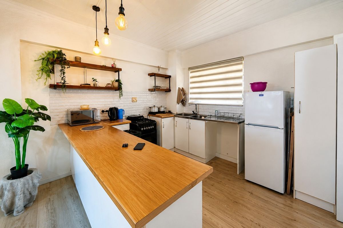 A functional kitchen featuring a wooden breakfast bar, subway tile backsplash, open shelving, and modern cabinetry with integrated sink and stove.