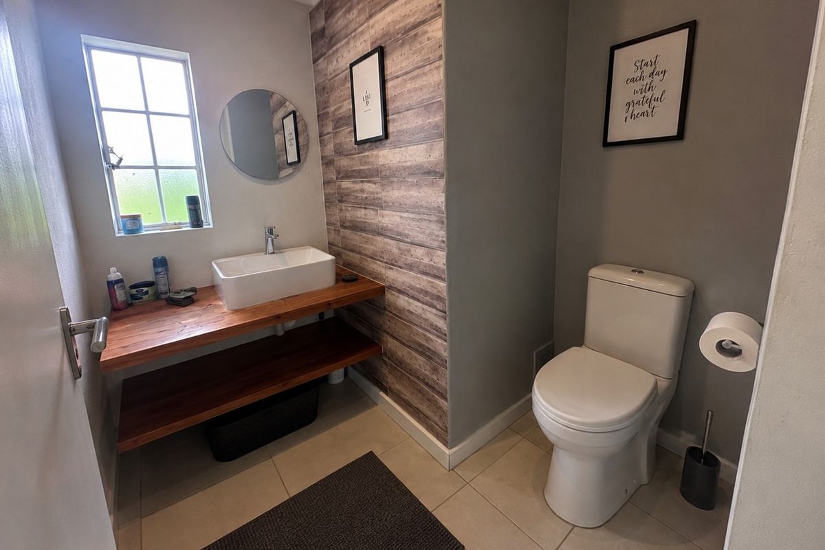 A modern bathroom featuring a timber vanity with a vessel sink, a tiled feature wall, and a standard toilet.