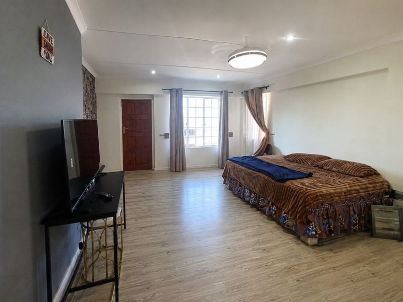 Spacious bedroom featuring laminate flooring, recessed lighting, and a large window with security bars, offering a neutral canvas for personalization.