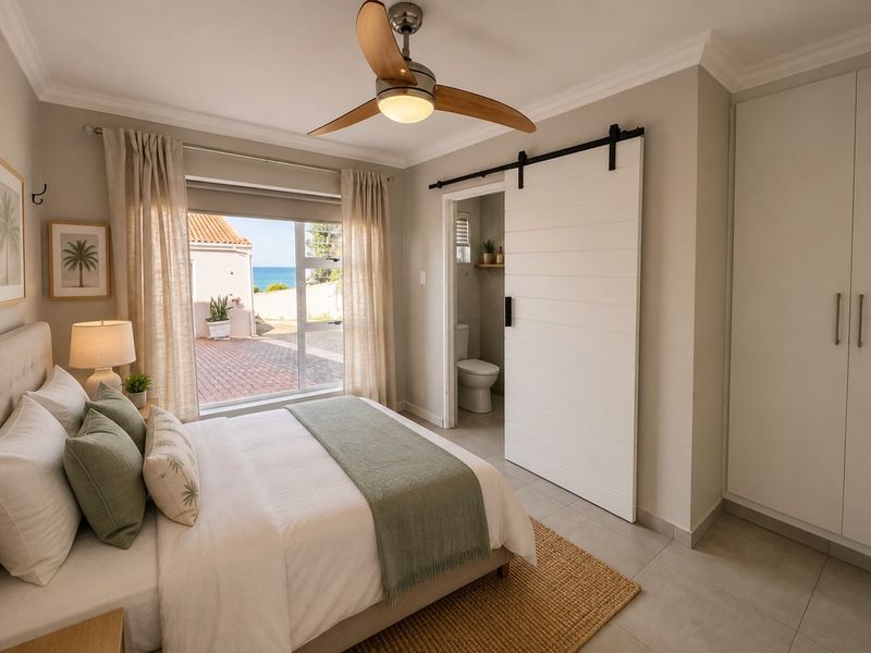 A well-maintained bedroom featuring a ceiling fan, built-in wardrobe, sliding barn door leading to an en-suite bathroom, and large window with exterior views.