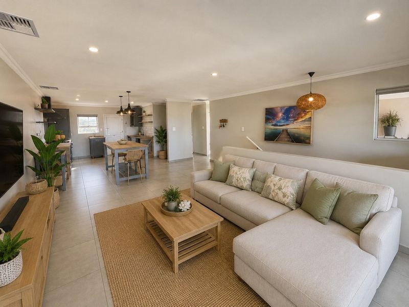 Spacious open-plan living and kitchen area featuring neutral tiled flooring, modern recessed lighting, and a functional kitchen layout with a central island.