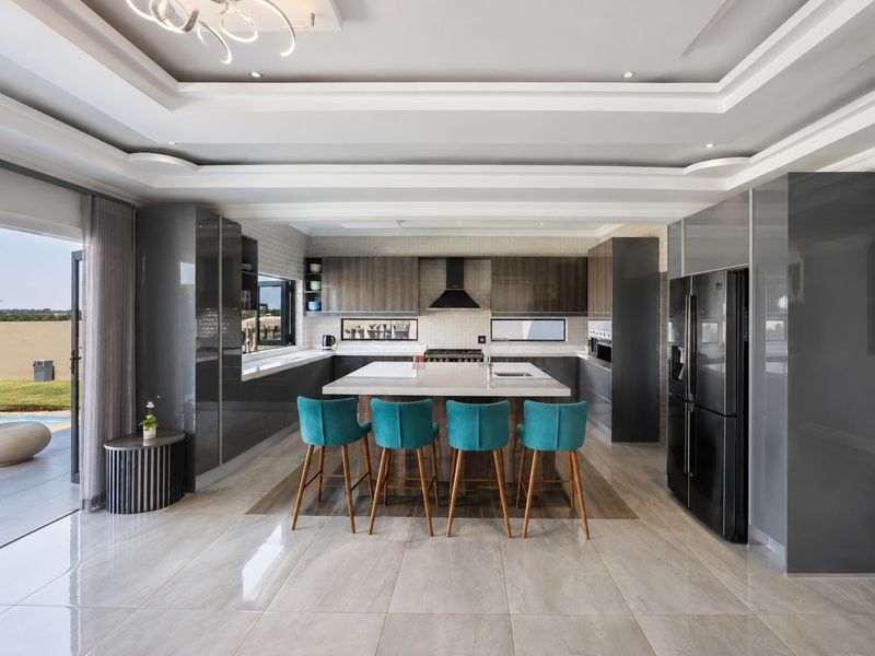Modern, high-end kitchen featuring a large central island, sleek cabinetry, stone countertops, and integrated appliances, with seamless access to an outdoor patio area.