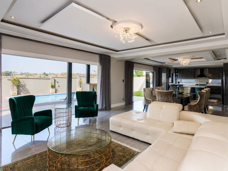 Spacious open-plan living and dining area featuring modern recessed ceilings, large sliding doors opening to the pool area, and a sleek integrated kitchen.