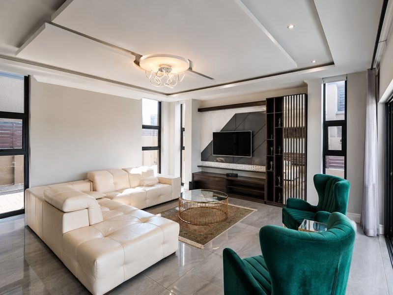 Modern living room featuring a custom built-in media unit, recessed ceiling design, large windows, and polished tiled flooring.