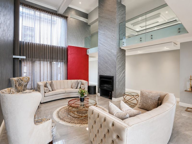 Spacious double-volume living room featuring a striking stone-clad fireplace, large floor-to-ceiling windows, and an elegant glass-railed mezzanine level.