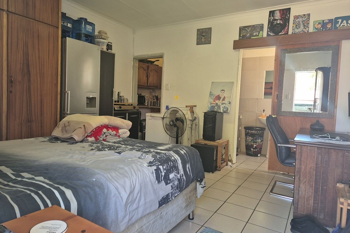 A bedroom featuring tiled flooring and built-in cupboards, with direct access to an en-suite bathroom area.