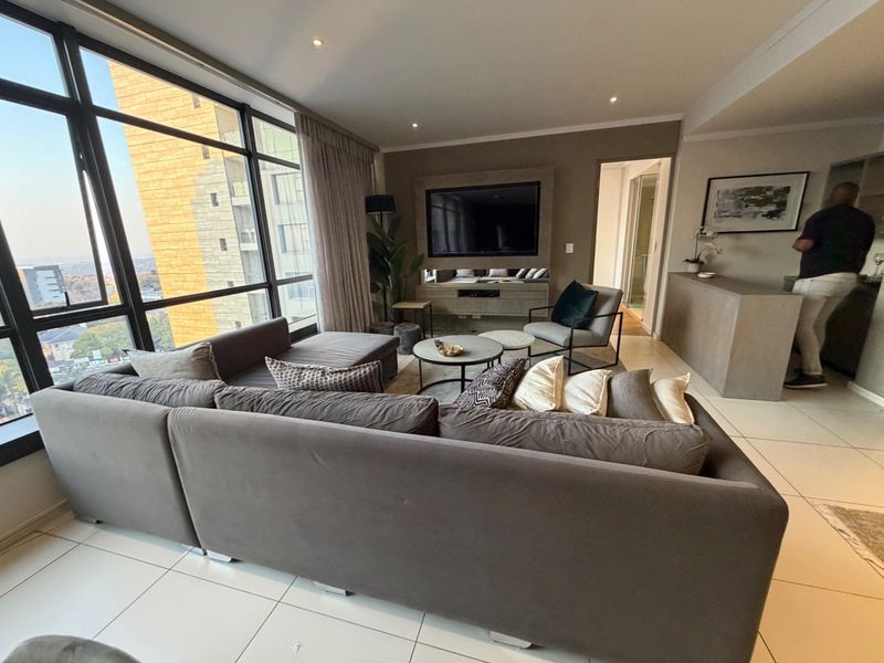 Modern living room featuring floor-to-ceiling windows with expansive views, tiled flooring, and a built-in media console.