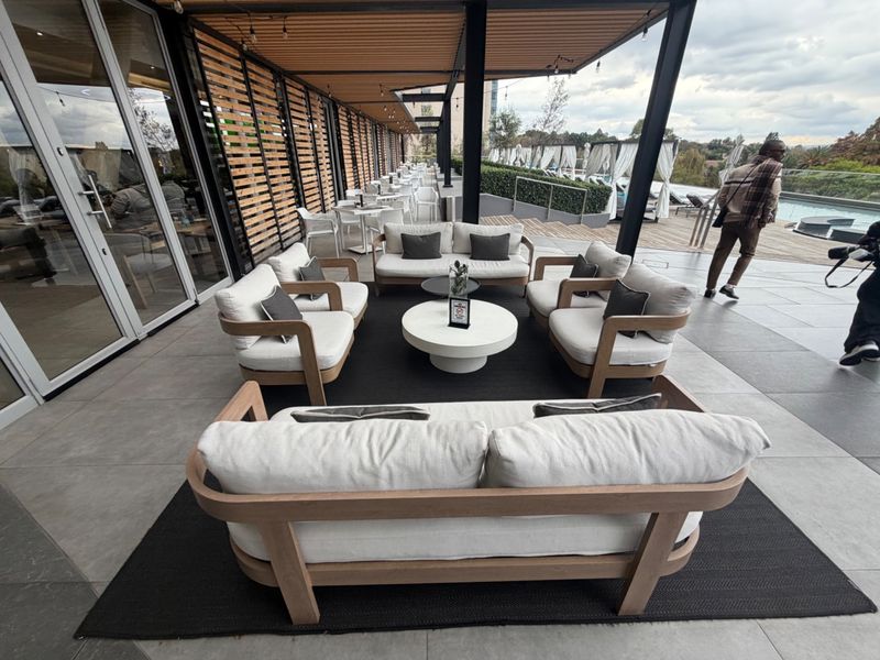A spacious, modern covered patio area featuring tiled flooring, timber slat screens, and direct access to the pool area through large glass sliding doors.