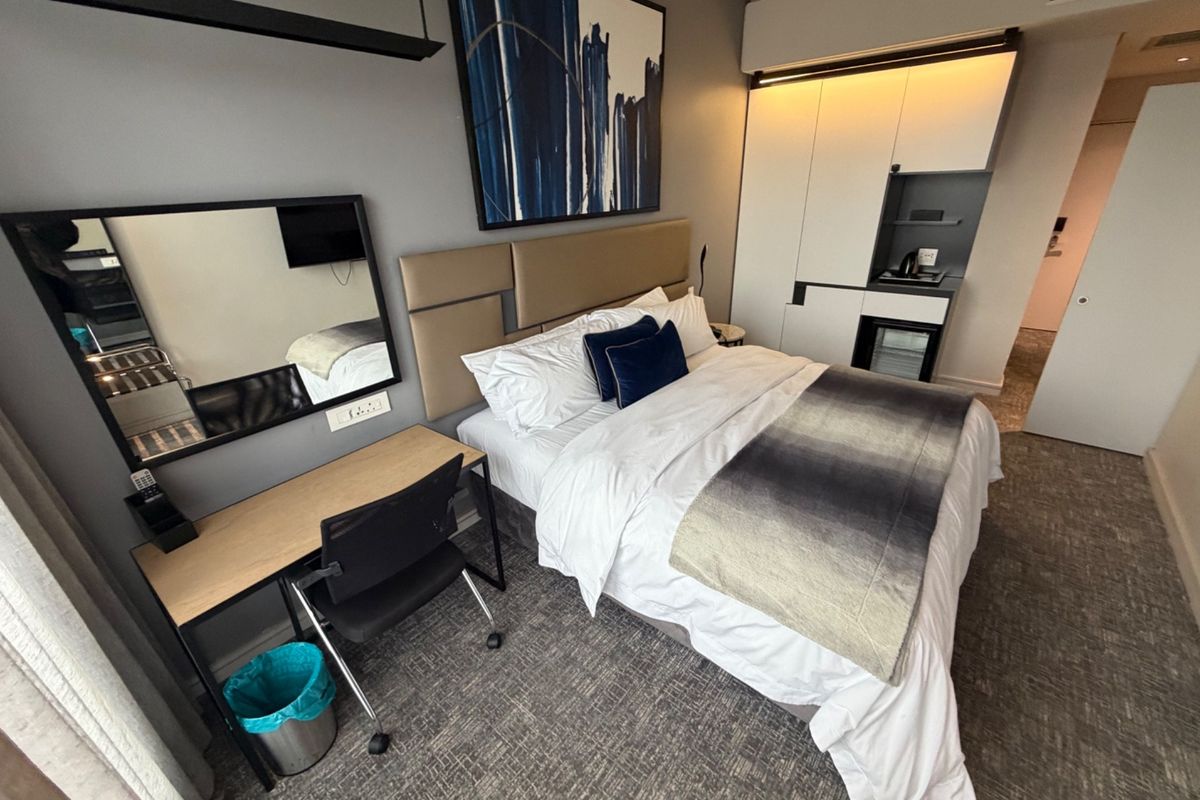 A modern bedroom featuring a built-in wardrobe with integrated lighting, neutral wall tones, and carpeted flooring.