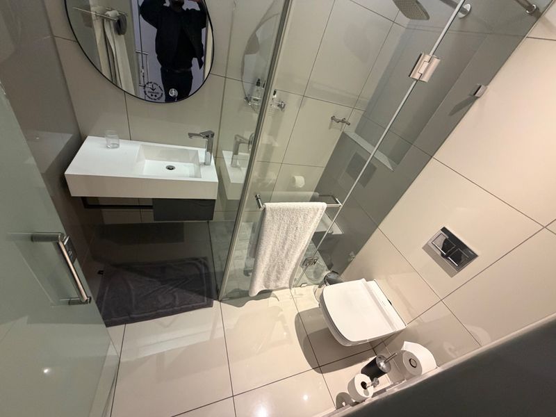 Modern bathroom featuring a wall-mounted vanity, glass shower enclosure, and wall-hung toilet with high-quality tiled finishes.