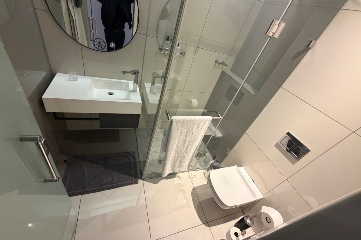 Modern bathroom featuring a wall-mounted vanity, glass shower enclosure, and wall-hung toilet with high-quality tiled finishes.