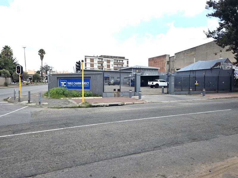 Commercial property exterior featuring a paved driveway, secure perimeter fencing, and prominent street-facing signage located on a corner lot.