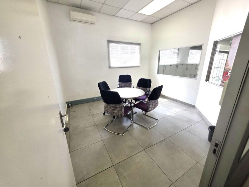 A functional office space featuring tiled flooring, a drop ceiling with integrated lighting, an air conditioning unit, and an internal glass partition.