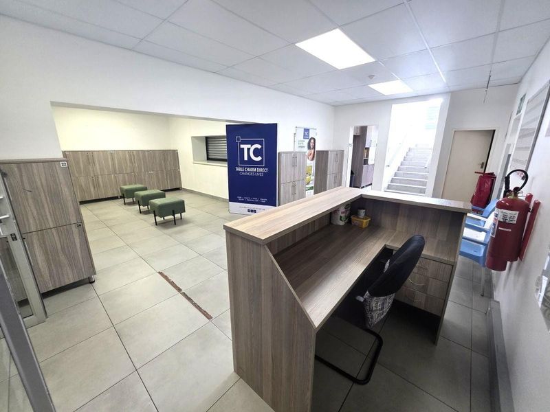 Commercial reception area featuring a built-in service desk, extensive locker storage, tiled flooring, and a suspended ceiling with recessed lighting.