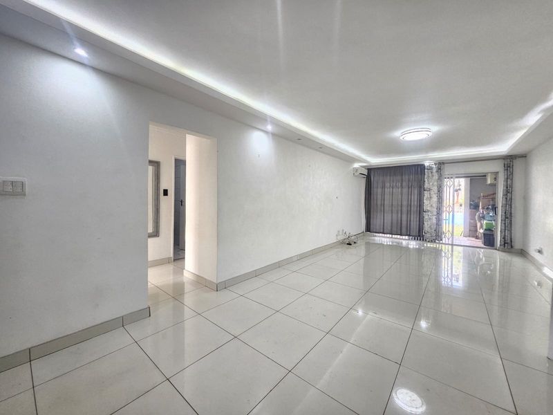 Spacious, empty living area featuring polished tiled flooring, recessed ceiling lighting, and a split-system air conditioner, with direct access to an outdoor patio area.