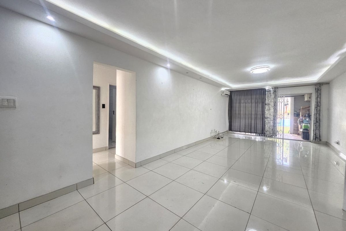 Spacious, empty living area featuring polished tiled flooring, recessed ceiling lighting, and a split-system air conditioner, with direct access to an outdoor patio area.
