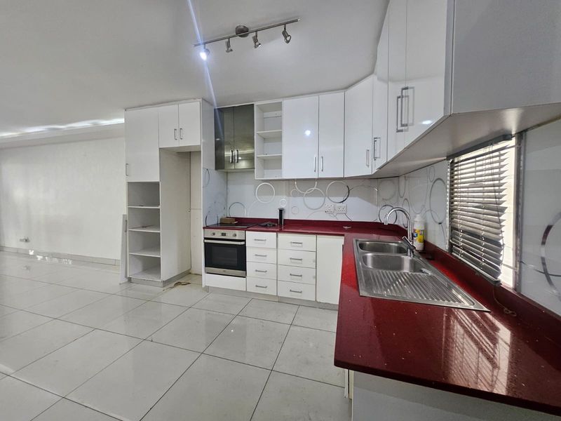 A functional kitchen featuring white cabinetry, a bold red countertop, built-in oven, and tiled flooring, offering a clean canvas for modern updates.