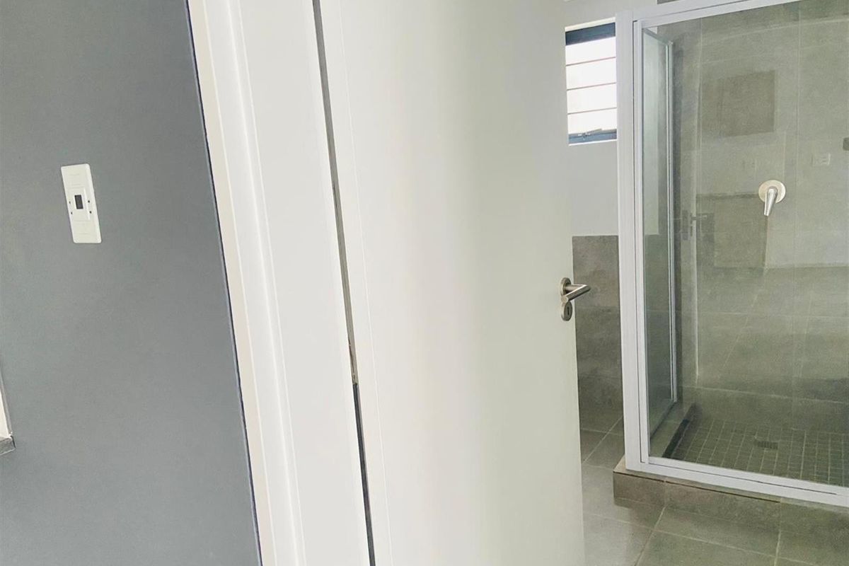 A clean, modern bathroom featuring a glass-enclosed shower with neutral grey tiling and contemporary fixtures.