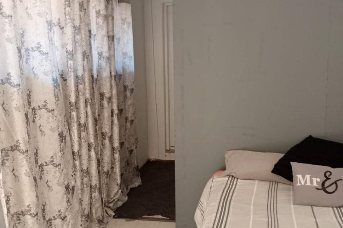 A bedroom featuring tiled flooring and a grey accent wall, requiring minor cosmetic updates to improve the overall finish and aesthetic appeal.