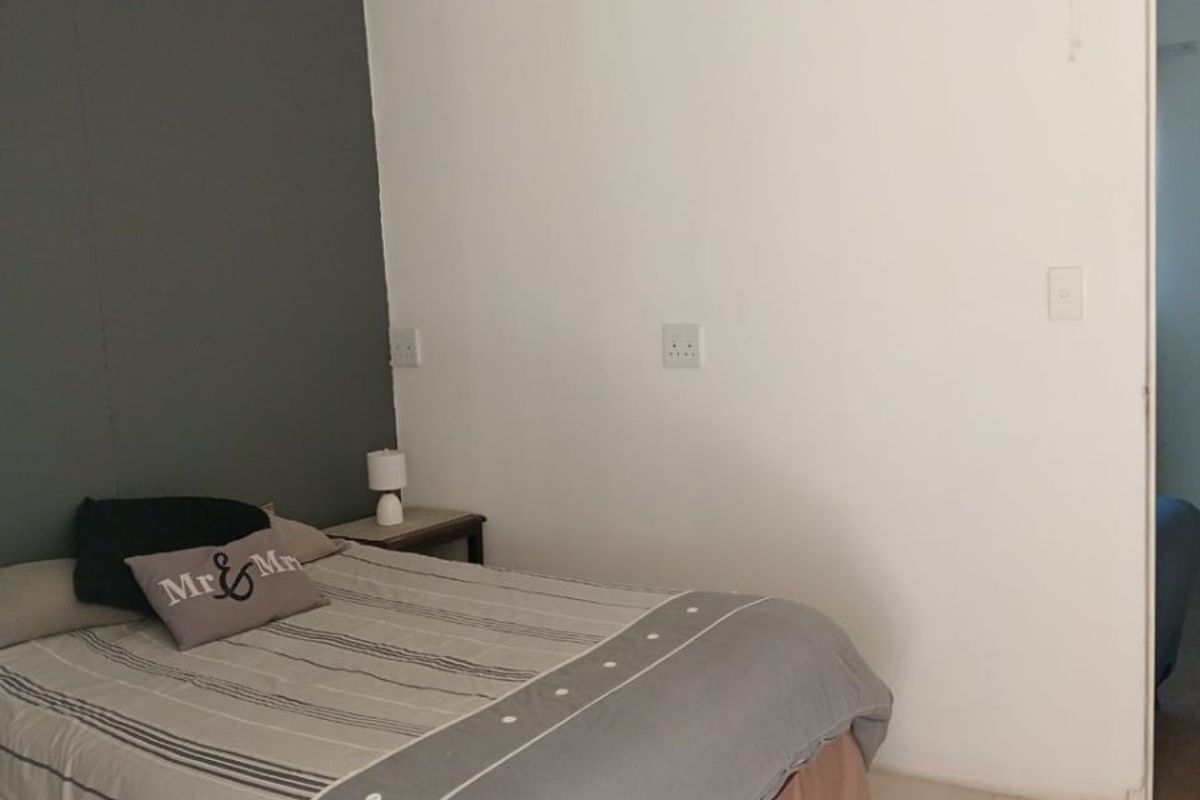 A bedroom featuring tiled flooring, a ceiling fan, and a grey accent wall.