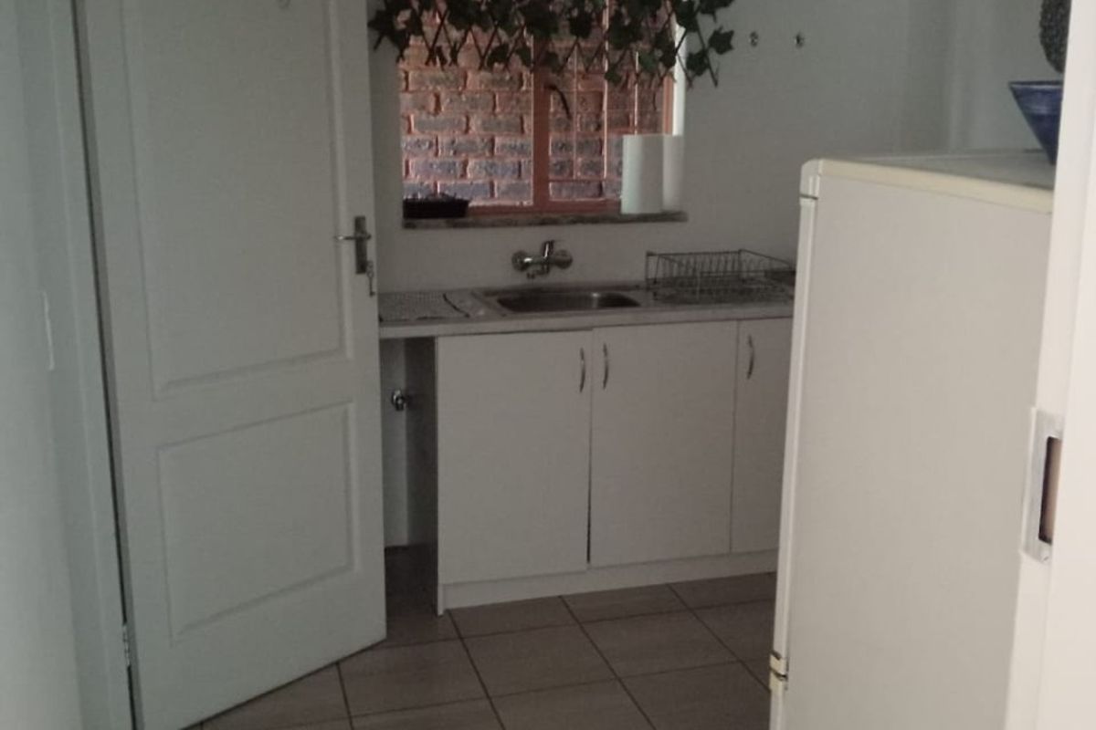 A functional scullery area featuring tiled flooring, built-in cabinetry, and a sink, providing additional utility space for the apartment.