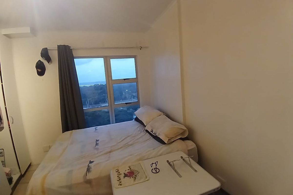 A bedroom featuring a built-in wardrobe and large window with views, providing natural light and functional storage space.