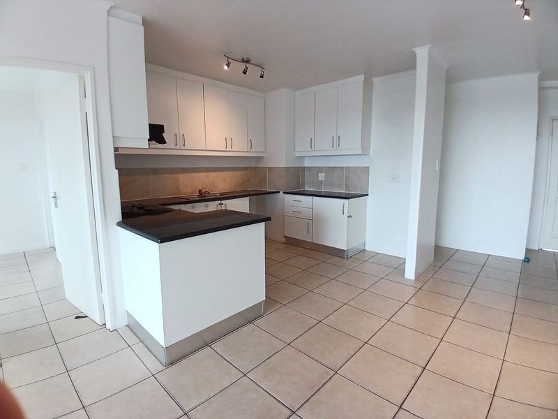 A clean, functional kitchen featuring white cabinetry, dark countertops, tiled backsplash, and ceramic flooring, offering a neutral space ready for personalization.